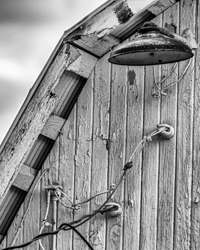 A porcelain barn light blends into a still life of crackled paint, aged wiring, and weathered wood.