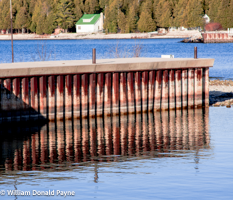 The pier at Ellison Bay Park casts reflections into the shallow shore waters of Green Bay, WI.