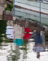 Watchers on a Sister Bay dock cast colorful reflections like flags rippling in the water.