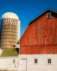 At Bea's Ho-Made Products in Gills Rock, Wisconsin, a bold cerulean sky, a classic red barn, and a white capped silo provide the colors, shapes, and textures for an architectural composition whose strong geometry and confident lines speak of pride, precision, and permanence.