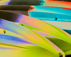 The sun lights up a stack of kayaks into a pastel rainbow.